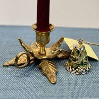 Brass holly leaf candle holder and cloisonné snuffer with candle inserted