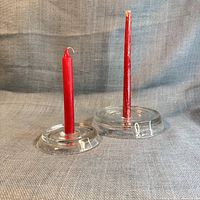 Two glass candle holders with red candles in place