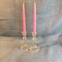 Two Lenox glass candlestick holders with pink taper candles inserted