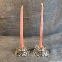 two pressed glass candleholders with pink taper candles inserted