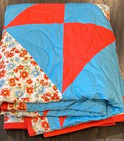 Folded quilt showing floral, red, and blue patch design