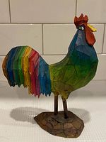 Right side view of multicoloured carved wood rooster on small base