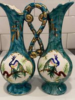 Front view of both teal ceramic peacock pitcher vases