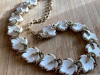 Close view of necklace links showing white leaves and gold-tone wraps