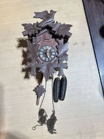 Front view of carved wood cuckoo clock with weights and chains attached