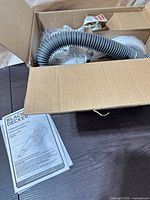 Box contents showing flexible hose and wrapped components with manual visible