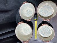Top view of four bowls showing cream interior with blue floral pattern and brown beaded rims
