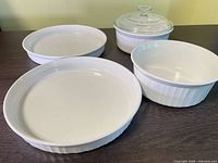 All four ceramic dishes and glass lid arranged on table