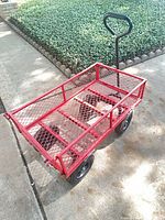 Full view of red mesh wagon with black handle and wheels