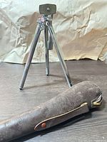 Tripod standing extended with leather case in foreground
