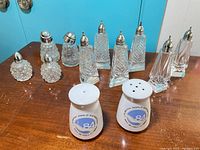 Front and angled view of all 12 shakers showing styles and ceramic markings