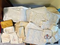 Stack of assorted vintage linens including runners, napkins, placemats, crocheted lace and embroidered pieces