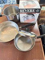 All cookware and boxed tea kettle grouped on table