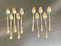 Ten silver-plated teaspoons arranged in two groups of five, displaying differing handle patterns.