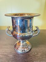 Full view of silver-plated ice bucket on pedestal with two handles