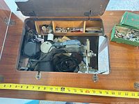 Machine folded into wooden cabinet with accessories visible