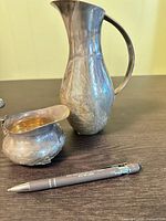 Creamer and pitcher on tabletop showing overall forms and tarnish