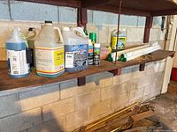 Shelf with jugs of washer fluid, cleaners, aerosol cans and fluorescent tubes
