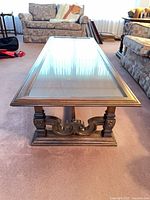 Coffee table end view showing carved base and glass top