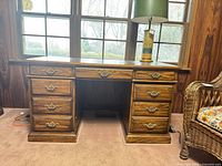 Front view showing nine-drawer Kaufman desk with leather inlay top and brass pulls