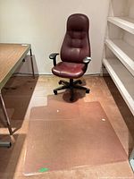 Front view of burgundy high-back office chair on floor protector