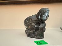 Front view of Inuit carved stone figure with tape showing 4.25 in height