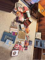 Wide view of approximately 40 books spread on carpet, various genres and bindings visible