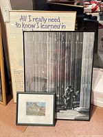 Three framed artworks leaning together: Fulghum text poster, Hampton black-and-white poster, Blackadar cricket print