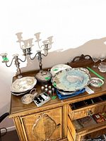 Sideboard view of all silverplate pieces, trays stacked, candelabra, covered dish, shakers, flatware visible