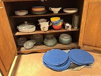 cabinet interior showing variety of plates, bowls, casserole, ramekins, placemats