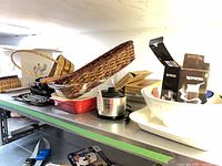 Shelf view showing Crock-Pot, red baking dish, wicker baskets, Nespresso boxes, roasting rack