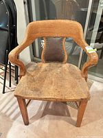 Front view of oak armchair showing open arms, leather back panel, overall wear