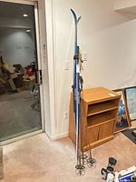Full view of skis and three poles leaning against wall