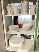 Cabinet shelves showing stacks of dinner plates, salad/bread plates, saucers, teacups and mugs