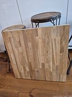 Front view of square butcher block panel leaning against stools