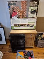 Full view of boxed PetSafe Pet Loo, folded wire crate, plastic bin of toys