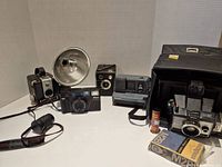 Group shot of five cameras with flash, grip and film