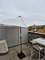 Entire umbrella set up on patio, canopy open, base visible