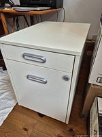 Front view of white two-drawer filing cabinet showing handles and lock