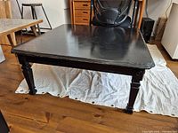 Full view of black square coffee table on drop cloth