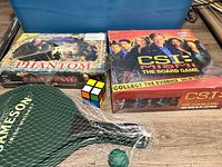 Overall lot with two sealed board games, Jameson paddles set, green ball, mini Rubik’s cube