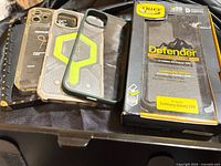 Stack of four smartphone cases and boxed OtterBox Defender case