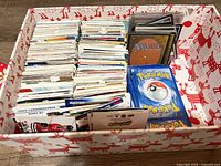 Box with large quantity of mixed trading cards neatly stacked