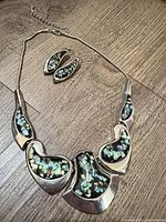 Full view of necklace with matching earrings displayed on wood surface