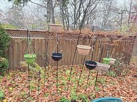 multiple metal shepherd hooks with attached planters standing in garden setting