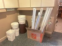 Plastic buckets beside box containing several fluorescent light fixtures