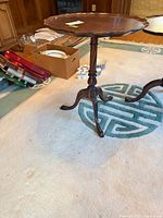 Full view of tilted side table showing tripod base and surrounding items