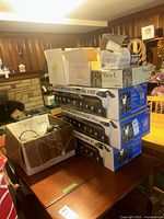Stacked view showing three stainless steel solar light set boxes, two Vega-L boxes, multiple Philips bulb boxes, SensorLite fixture box, citronella clip-on