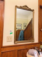 Full front view of ornate gold framed wall mirror mounted on wall