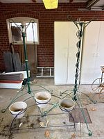 Two green shepherd’s-hook stands, one black demi-lune stand with three beige pots